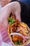 Female hand holding a vegetarian taco above a plastic basket