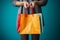 Female hand holding vibrant shopping bags on a blue backdrop