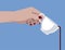 Female hand holding a white cup with pouring coffee on blue background