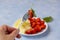 Female hand holds a berry on a fork. Fresh organic vegetarian fruit salad
