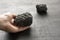Female hand holds a black stone of lava and magma from the volcano Etna on the island of Sicily, Italy. Stone after the eruption