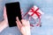 A female hand holds a cell phone and a finger presses on a blank black screen for shopping goods on the Internet