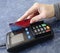 The female hand holds a credit card on the payment terminal. online shopping, contactless payment