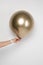 A female hand holds an inflated golden matte ball on a white background. Valentine\'s day gift