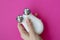 Female hand holds a microcurrent facial toning device on a pink background. A cosmetology device for home self-care