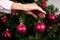 Female hand holds red decoration ball for Christmas tree