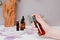 Female hand holds a spray bottle with facial cosmetics, amber bottles with liquid on a tray on the wooden table