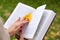 Female hand holds yellow leaf on an open book. Autumn background or postcard