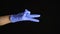 Female hand in a latex medical glove makes an peace gesture isolated on black background