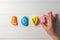 Female hand laying out text Love written on colored pebbles on white wooden surface. Flat lay. Copy space