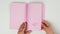 Female hand leafing through notepad with blank pink pages on white table