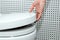 Female hand lifts the lid of the toilet bowl, close-up. The concept of personal hygiene