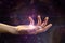 Female hand with light coming from the palm, against the background of the galaxy. The concept of divination, mysticism