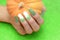 Female hand with long nail design. Glitter gold and white nail polish manicure. Female hand with perfect manicure hold pumpkin