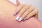Female hand with long nails with glitter nail polish. Long pink nail design. Women hand with sparkle manicure on glitter