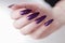 Female hand with long nails and purple plum manicure