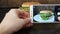 Female hand makes photo on the smartphone of a beautiful juicy hamburger with lettuce leaves on a stylish wooden