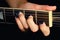 Female hand with manicure lying on the wooden neck of the guitar. Woman guitarist clamped a chord on the strings of the musical