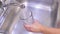 Female hand opening faucet and pouring water in glass on kitchen