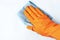Female hand in orange glove wipes surface with a rag, white background