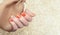 Female hand with orange nail design. Glitter orange nail polish manicure. Smile symbol nail art decoration. Copy space