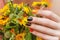 Female hand with orange nail design holding flowers.
