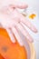 Female hand orange paraffin wax in bowl. Manicure.