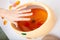 Female hand and orange paraffin wax bowl. Woman in beauty salon