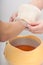 Female hand and orange paraffin wax bowl. Woman in beauty salon