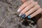 Female hand with pearly nail design. Glitter blue nail polish manicure. Woman hand with white dried flower