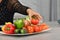 A female hand picking up a delicious looking tomato from a plate with assorted vegetables