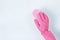 Female hand in pink glove wipes surface with rag, isolated on blue background
