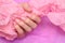 Female hand with pink nail design. Pink nail polish manicured hand. Female hands hold crumpled paper on pink background