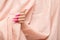 Female hand with pink stiletto nail design. Long nail polish manicure. Woman hand on rose fabric background