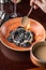 Female hand pouring sauce on black dumplings on orange plate