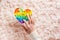 A female hand presses a silicone rainbow antistress toy on a background of fluff. A modern way to relax