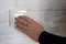 Female hand pushes button of white Switch on brick wall. Close-up. Copy space