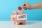 Female hand puts heart in piggy bank text Donate against blue background