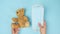 Female hand puts stack of disposable medical face masks near brown teddy bear