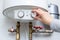 Female hand puts thermostat of electric water heater boiler in low low power consumption mode