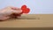 Female hand putting red heart sign in cardboard box, donation center, medicine