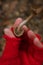 Female hand in red knit mitten holding little brown mushroom on unfocused forest background. Autumn mushrooms picking