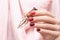 Female hand with red nail design. Glitter red nail polish autumn manicure. Woman hand hold red dry autumn rose flower