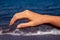 Female hand with red sunburn skin on blue sea background. Sun burned skin peeling. Seaside threat