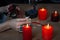 A female hand with rings, holding the Gyfu rune, surrounded by burning candles