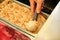 Female hand with scoop takes hazelnut ice cream from fridge and steel service containers. Woman taking scoop of tasty ice cream.