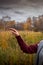 Female hand with scruffy manicure against the backdrop of an autumn forest and a gloomy sky. Stupid gesticulation