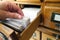 Female hand searching through archive cards in an old wooden filing cabinet in library