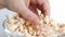 Female hand selects delicious fried popcorn from a large glass bowl, the concept of sweets, anticipation of interesting, exciting