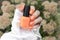 Female hand with short nails and orange neon manicure holds a bottle of nail polish